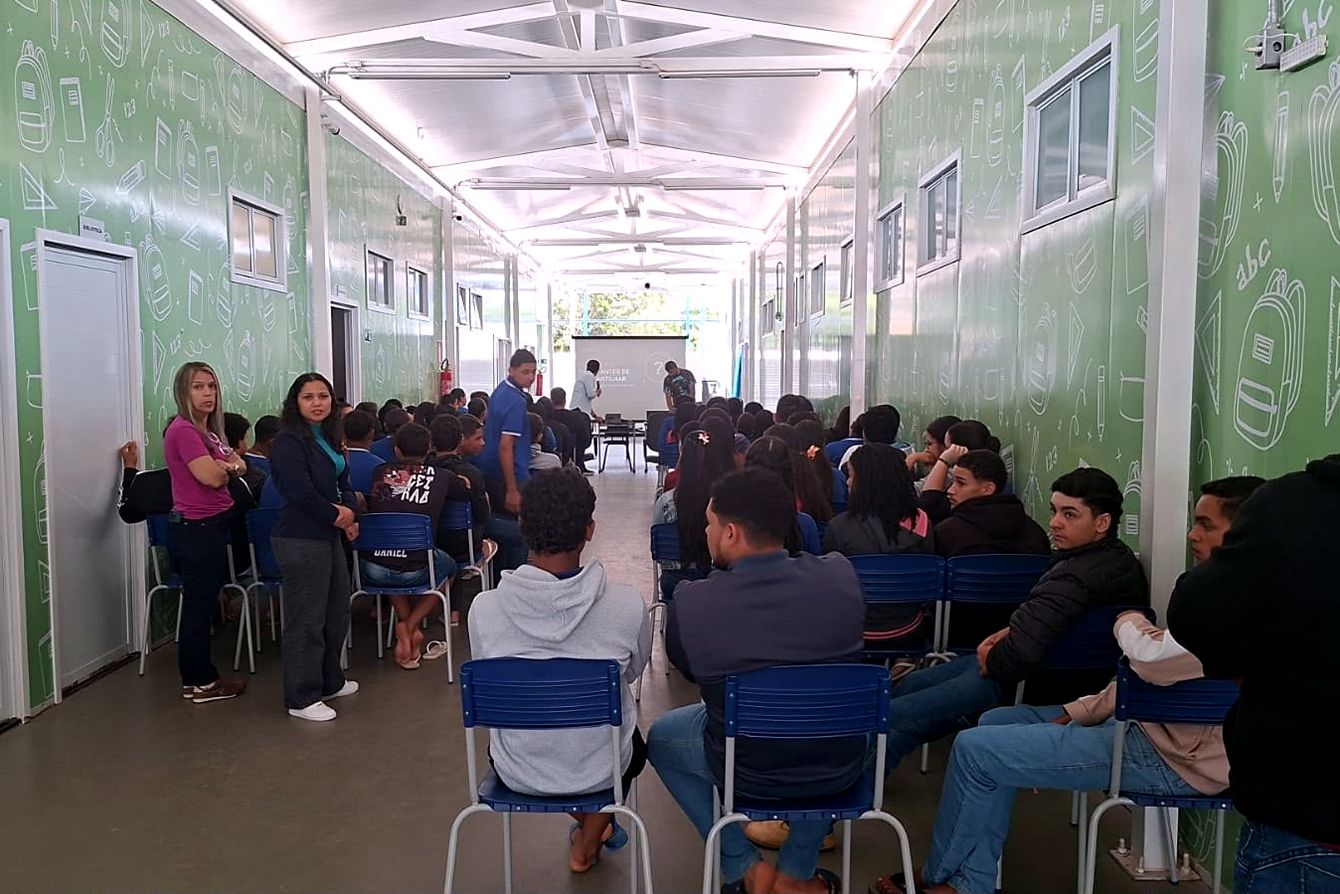 Estudantes reunidos no corredor da escola acompanham a palestra